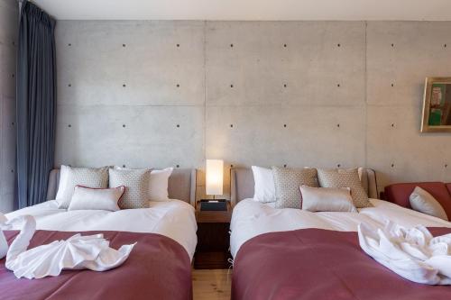 a room with two beds with white sheets at Tamatsukuri Daifuji Kan in Osaka