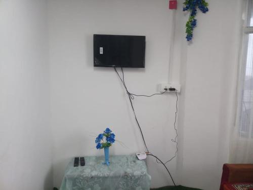 um quarto com uma mesa e uma televisão na parede em Vamoose Rhododendron em Darjeeling