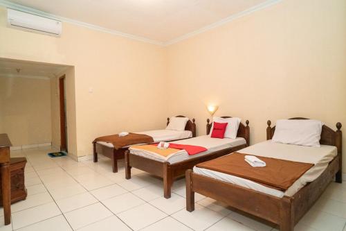 a room with three beds in a room at RedDoorz near Kampus 3 UTY Yogyakarta in Yogyakarta