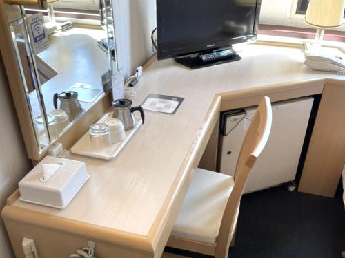 a desk with a television and a computer on it at Hotel The Centre Utsunomiya in Utsunomiya