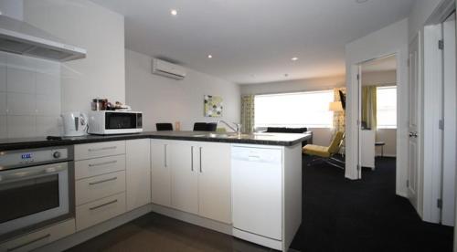 a kitchen with white cabinets and a stove top oven at Carramar Motor Inn in Palmerston North