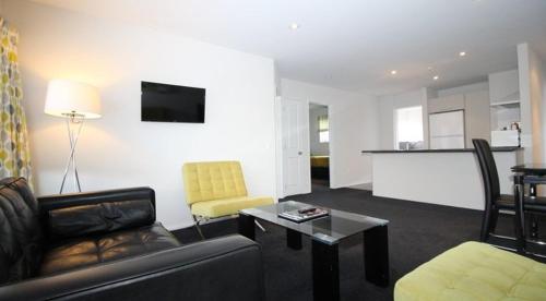 a living room with a couch and a table and a kitchen at Carramar Motor Inn in Palmerston North