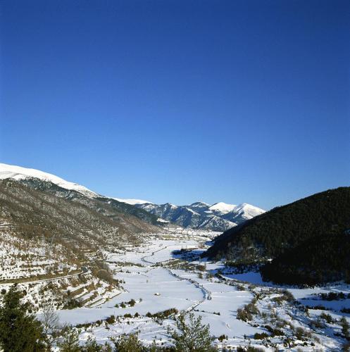 a snowy valley with a river and snow covered mountains at Hotel Rural El Pilaret in Azanúy