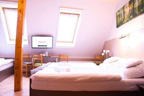 a bedroom with two beds and a flat screen tv at Huli Panzio in Tokaj