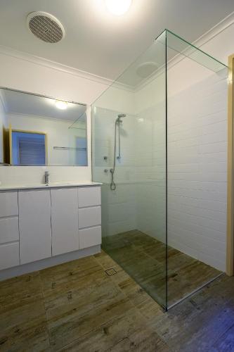 a bathroom with a glass shower and a sink at Pandanus Palms Holiday Resort in Point Lookout