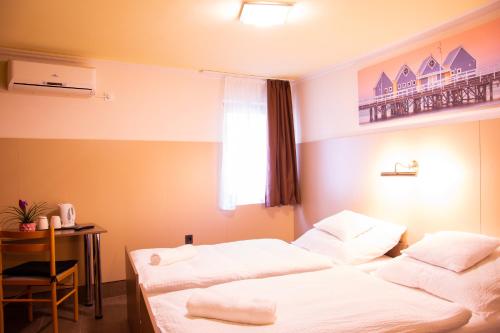a room with two beds and a table and a window at Huli Panzio in Tokaj