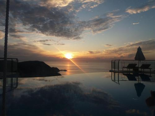 a reflection of the sunset in a swimming pool at Petani Bay Hotel - Adults Only in Vovikes