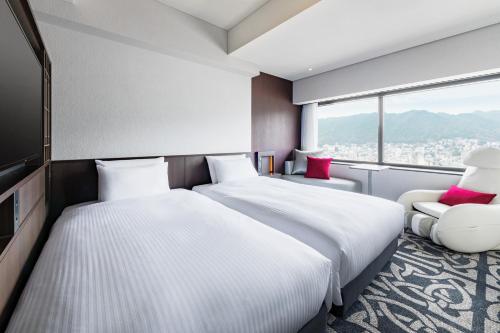 a hotel room with two beds and a chair at remm plus Kobe Sannomiya in Kobe