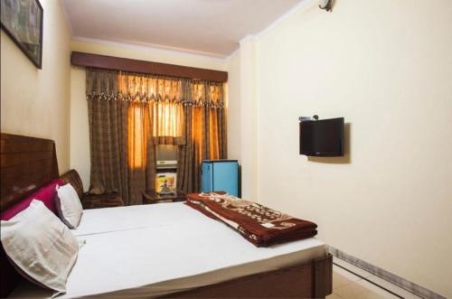 a bedroom with a bed and a tv on the wall at Vamoose Rama Palace in Gangānagar