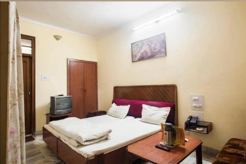 1 dormitorio con 1 cama y TV. en Vamoose Rama Palace en Gangānagar