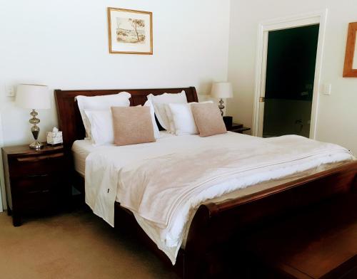 1 dormitorio con 1 cama grande con sábanas y almohadas blancas en Angaston Lodge, en Angaston