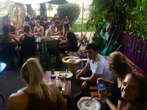 um grupo de pessoas sentadas em mesas em um restaurante em Backpackers By The Bay em Airlie Beach