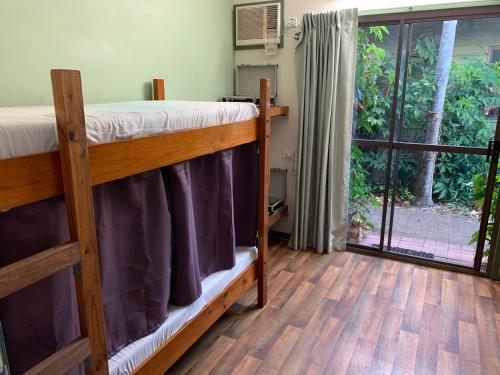 a room with two bunk beds and a sliding glass door at Backpackers By The Bay in Airlie Beach