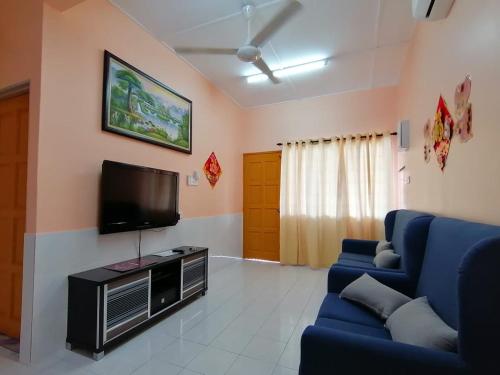 ein Wohnzimmer mit einem blauen Sofa und einem Fernseher in der Unterkunft Mui Gim Homestay 大港 美景民宿 in Sungai Besar