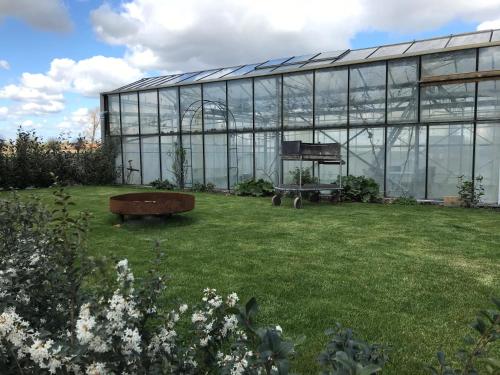 a large glass building with a bench in a yard at Grysperre B&B in Hooglede