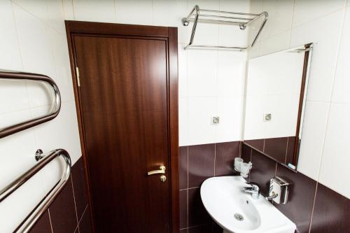 a bathroom with a sink and a wooden door at Seventh Heaven Hotel in Lazarevskoye