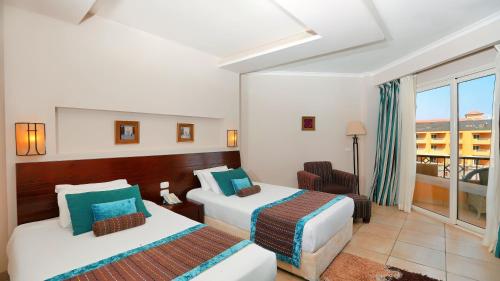 a hotel room with two beds and a balcony at Amwaj Beach Club Abu Soma in Hurghada