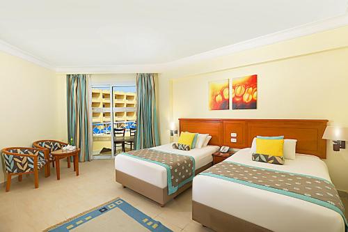 a hotel room with two beds and a chair at Amwaj Beach Club Abu Soma in Hurghada