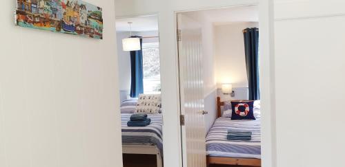 Cette chambre comprend 2 lits et un miroir. dans l'établissement Heated Swimming Pool Looe Polperro Cornwall Holiday Home, à Looe