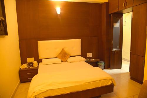 a bedroom with a large bed with a wooden headboard at Royal Palms Luxury Service Apartment in Nagpur