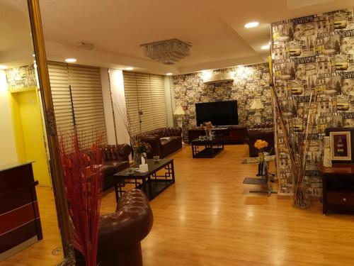 a living room with couches and tables and a television at Al Ghubrah Plaza Hotel in Muscat