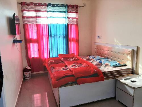 Schlafzimmer mit einem Bett mit roter Bettwäsche und einem Fenster in der Unterkunft CITY CROWN GUEST HOUSE in Sundarnagar