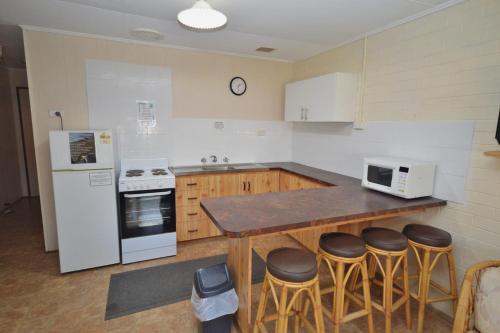 a kitchen with a counter and a refrigerator and stools at Red Rock Retreat C - Kalbarri WA in Kalbarri