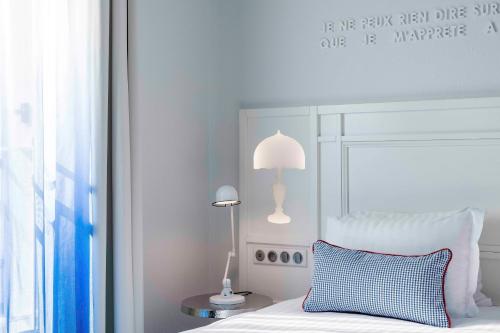 a bedroom with a white bed with a blue pillow and a lamp at Hotel 34B - Astotel in Paris