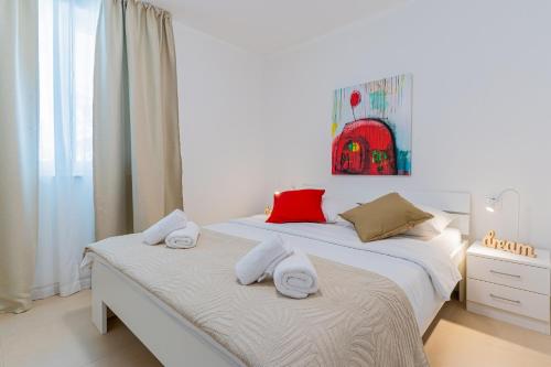 a white bedroom with two beds with towels on them at Apartments Lopari in Nerezine