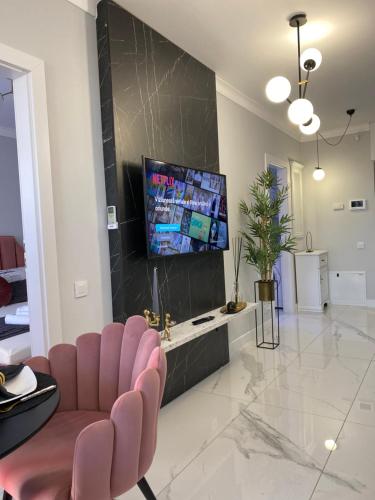 d'un salon avec des chaises roses et une télévision à écran plat. dans l'établissement Marble Apartments, à Oradea