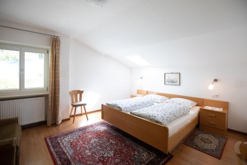 a bedroom with a bed and a chair and a window at Appartements Martinsheim in Tirolo
