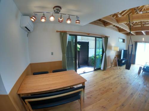 a dining room with a wooden table and a living room at CARA-YA(かーらやー） in Ishigaki Island