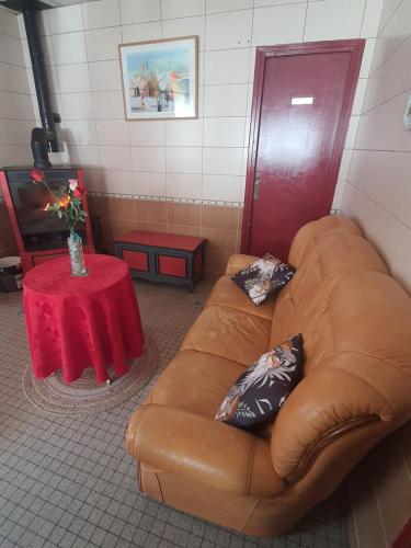 un sofá de cuero marrón en una habitación con mesa en Relais mm bessard, en Saint-Pierre-de-Varengeville