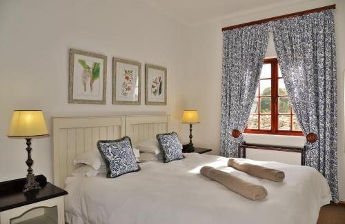 a bedroom with a white bed with two pillows and a window at De Hoop Collection - Opstal Houses in De Hoop Nature Reserve