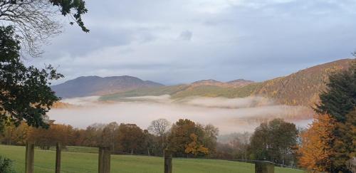 a view of a foggy valley with trees and mountains at Fairburn Activity Centre in Contin