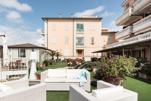 a patio with white furniture and a large building at Residenza Santa Cecilia in San Vincenzo