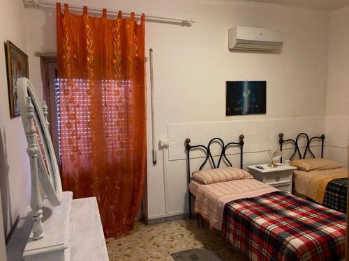 リド・ディ・オスティアにあるAppartamento Zia Gesinaのベッドルーム1室(ベッド2台、オレンジ色のカーテン付)