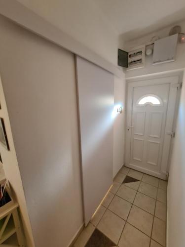 a hallway with a white door and a tile floor at Zseki apartman in Hajdúszoboszló