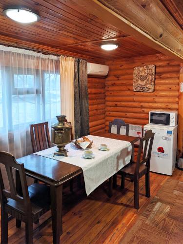 a dining room with a table and chairs and a kitchen at Котедж-парк Славна in Okhtyrka