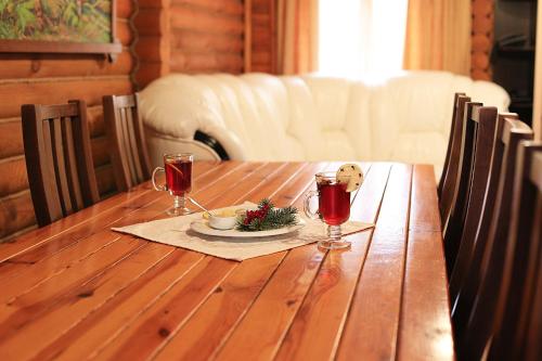 a wooden table with a plate of food and two wine glasses at Котедж-парк Славна in Okhtyrka