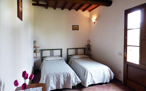 dwa łóżka w rogu pokoju w obiekcie Agriturismo San Fabio w mieście Castelnuovo Berardenga