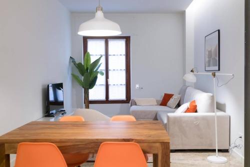 salon z drewnianym stołem i pomarańczowymi krzesłami w obiekcie Apartamentos Exclusivos en Calle Alfonso I w Saragossie