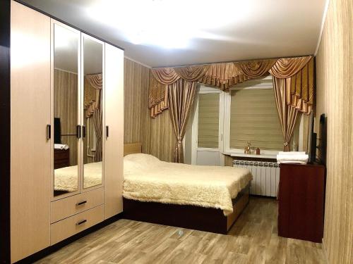 een slaapkamer met een bed en een grote spiegel bij Квартира in Saratov
