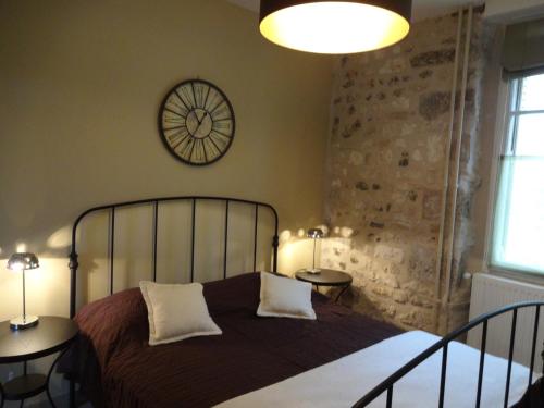 1 dormitorio con 1 cama con 2 mesas y reloj en Le Clos de l'Eglise - Inès, en Giverny