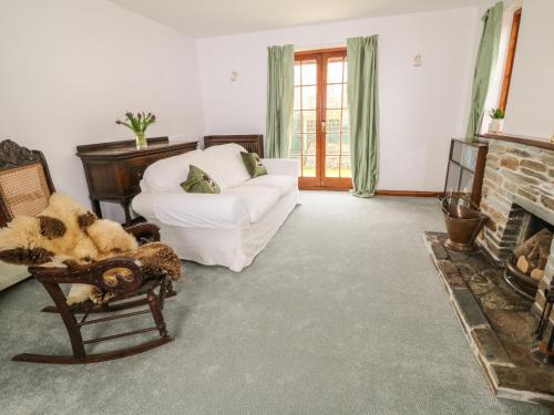 ein Wohnzimmer mit einer weißen Couch und einem Kamin in der Unterkunft Thrushel Cottage in Lifton