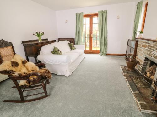 a living room with a white couch and a fireplace at Thrushel Cottage in Lifton