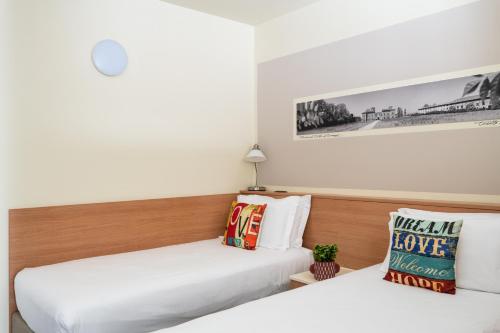 two beds in a hotel room with white sheets at Hotel Borgo Brianteo in Ponte San Pietro