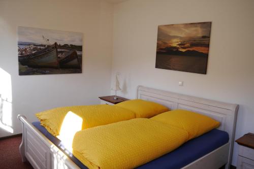 um quarto com uma cama com lençóis amarelos em Cafe Hotel Aroma Moselblick em Burgen