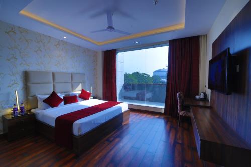 a bedroom with a large bed and a large window at The Vilana Hotel Rishikesh in Rishīkesh