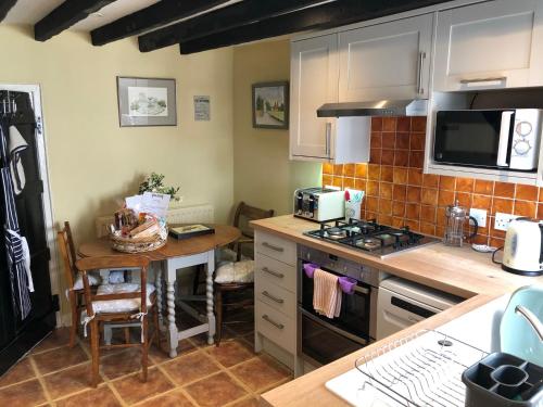 a kitchen with a sink and a stove top oven at Oriel Cottage in Pevensey